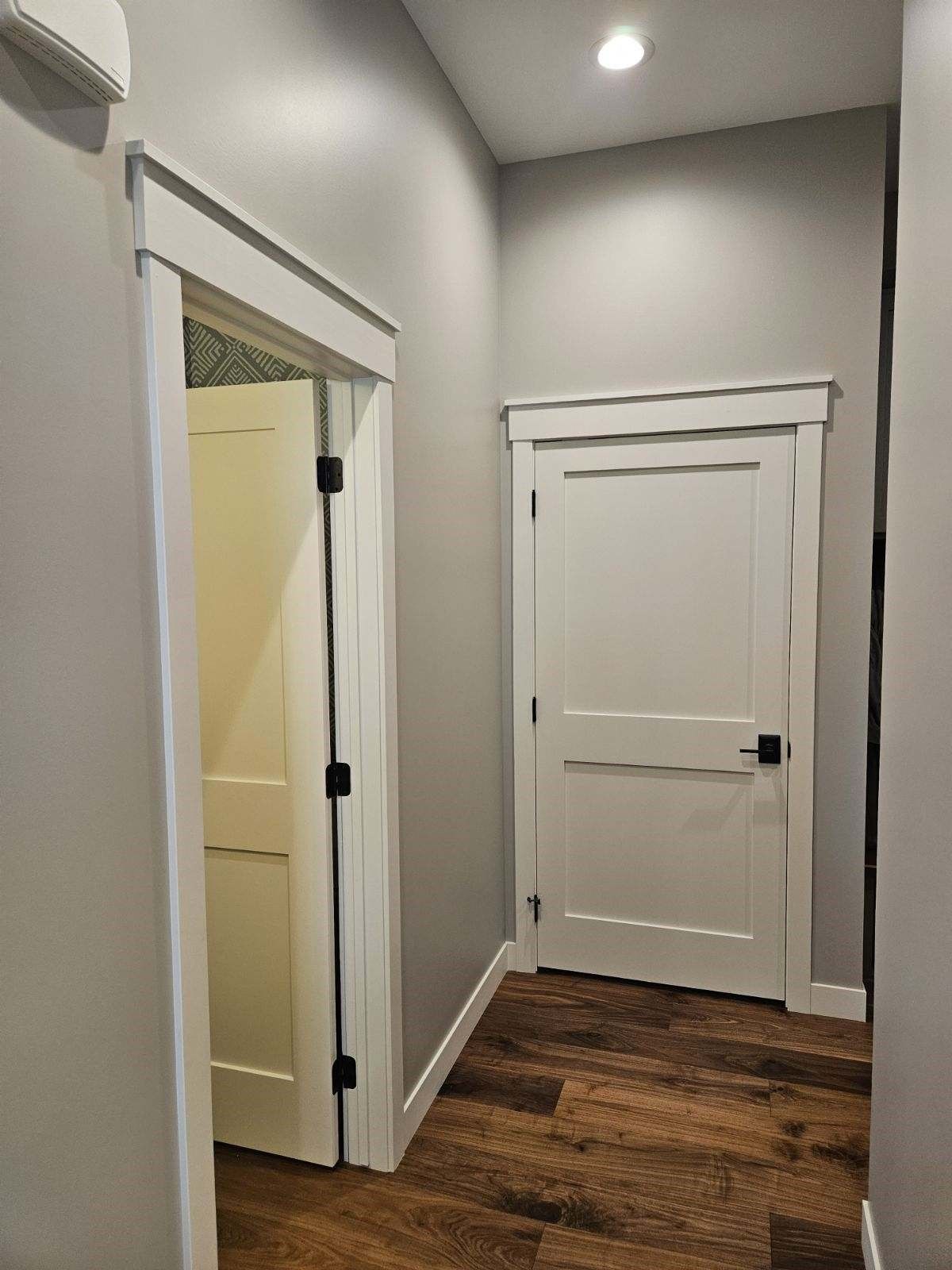 A hallway with two white doors and a wooden floor.