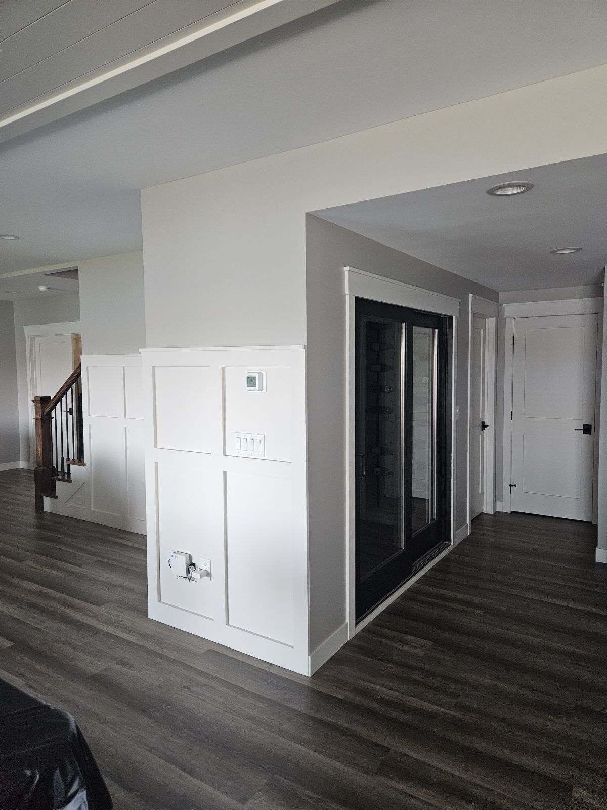 A living room with hardwood floors , white walls and sliding glass doors.