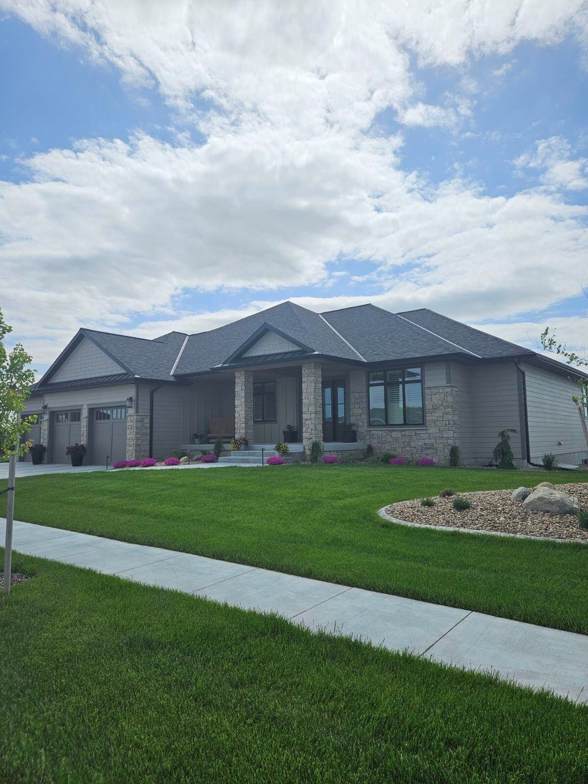 A large house with a lush green lawn and a gray roof.