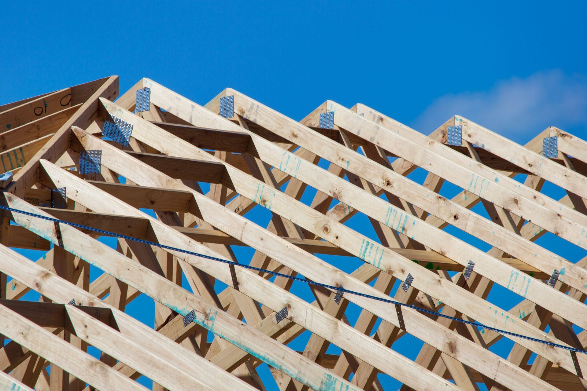 A roof is being built with wooden beams against a blue sky.