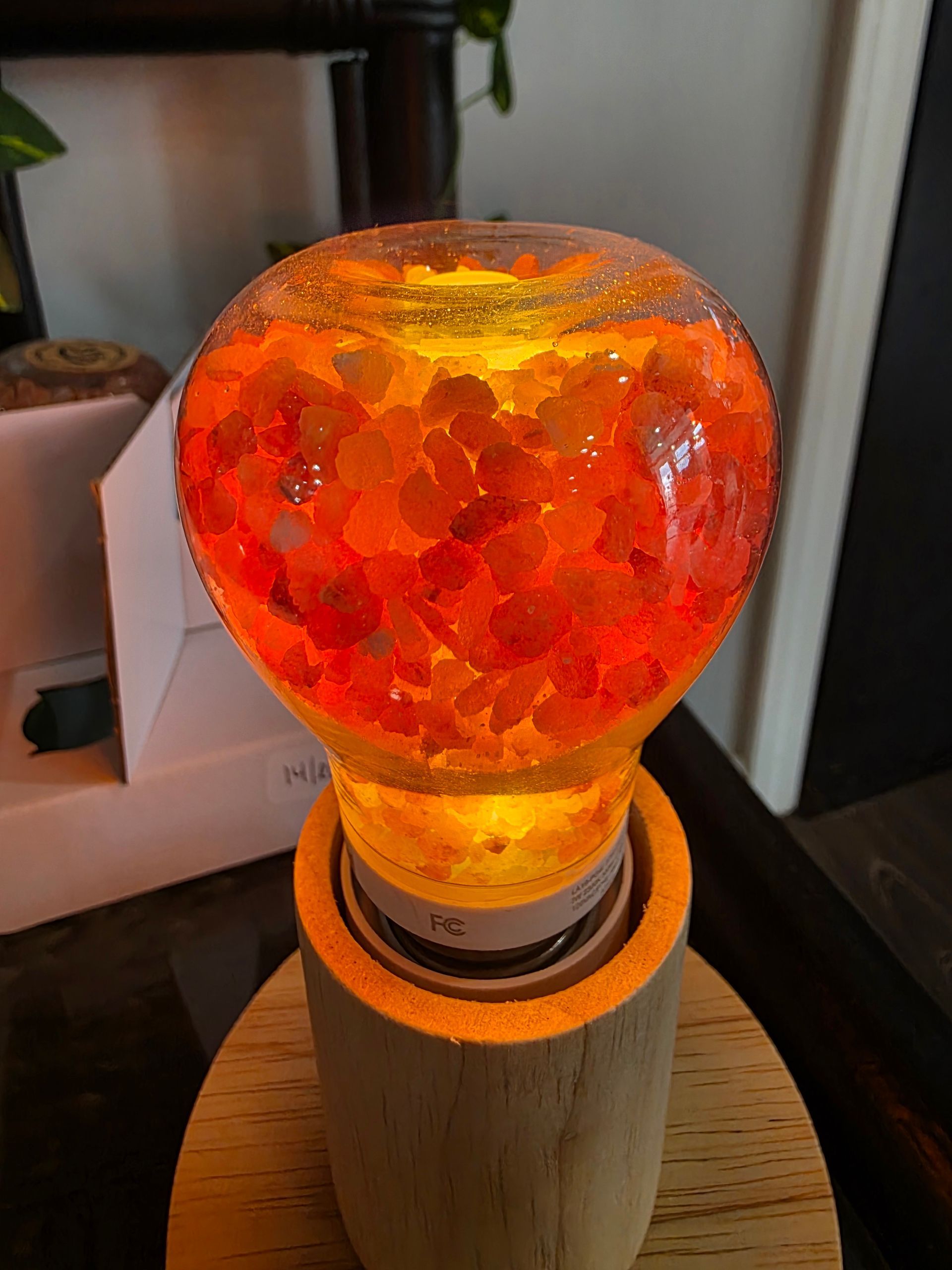 Orange glass lamp glowing on a wooden base, with a textured amber-red shade.