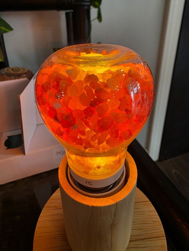 Orange cracked-glass lamp glowing on a wooden base in a dim room