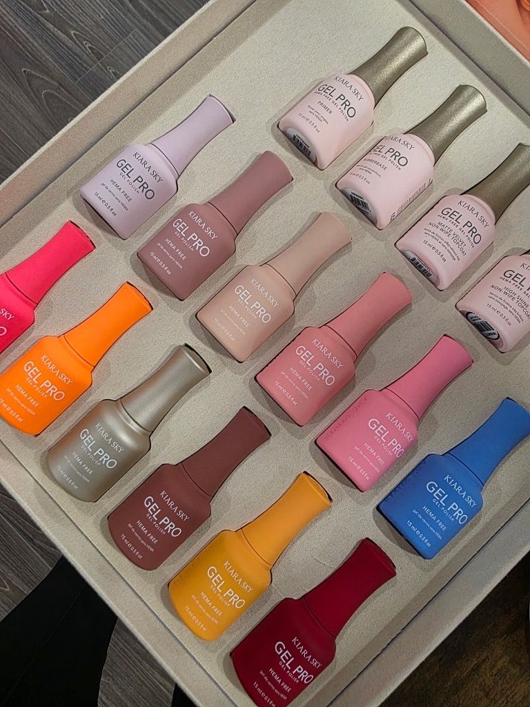 Assorted pastel and bright nail polish bottles arranged in a tray on a wooden surface.