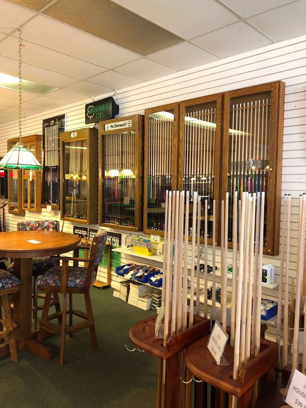 Display of pool cues and billiards accessories in a shop with wooden racks and tables