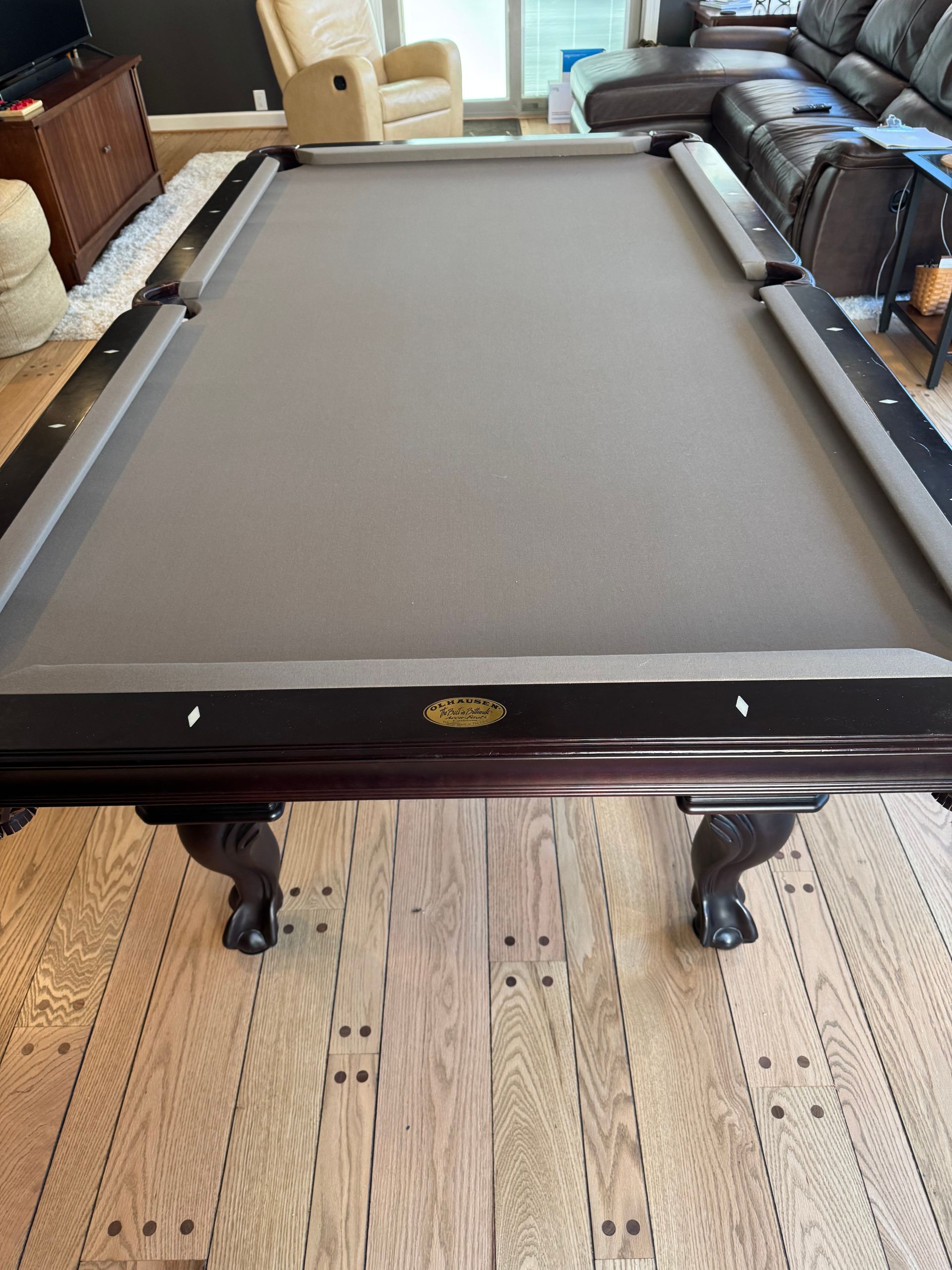 Pool table with gray felt in a room, centered on a patterned rug.