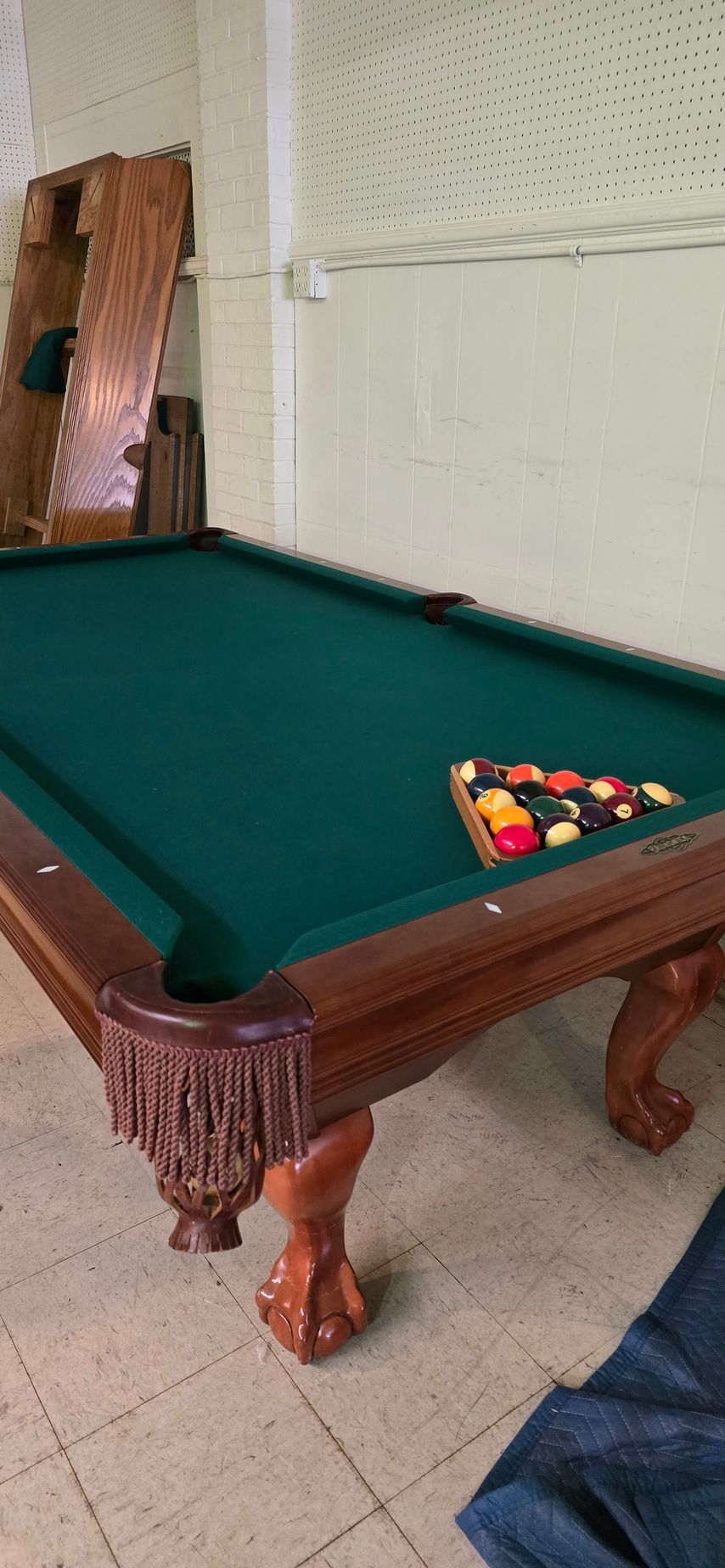 Green felt pool table with balls racked at one end in a room