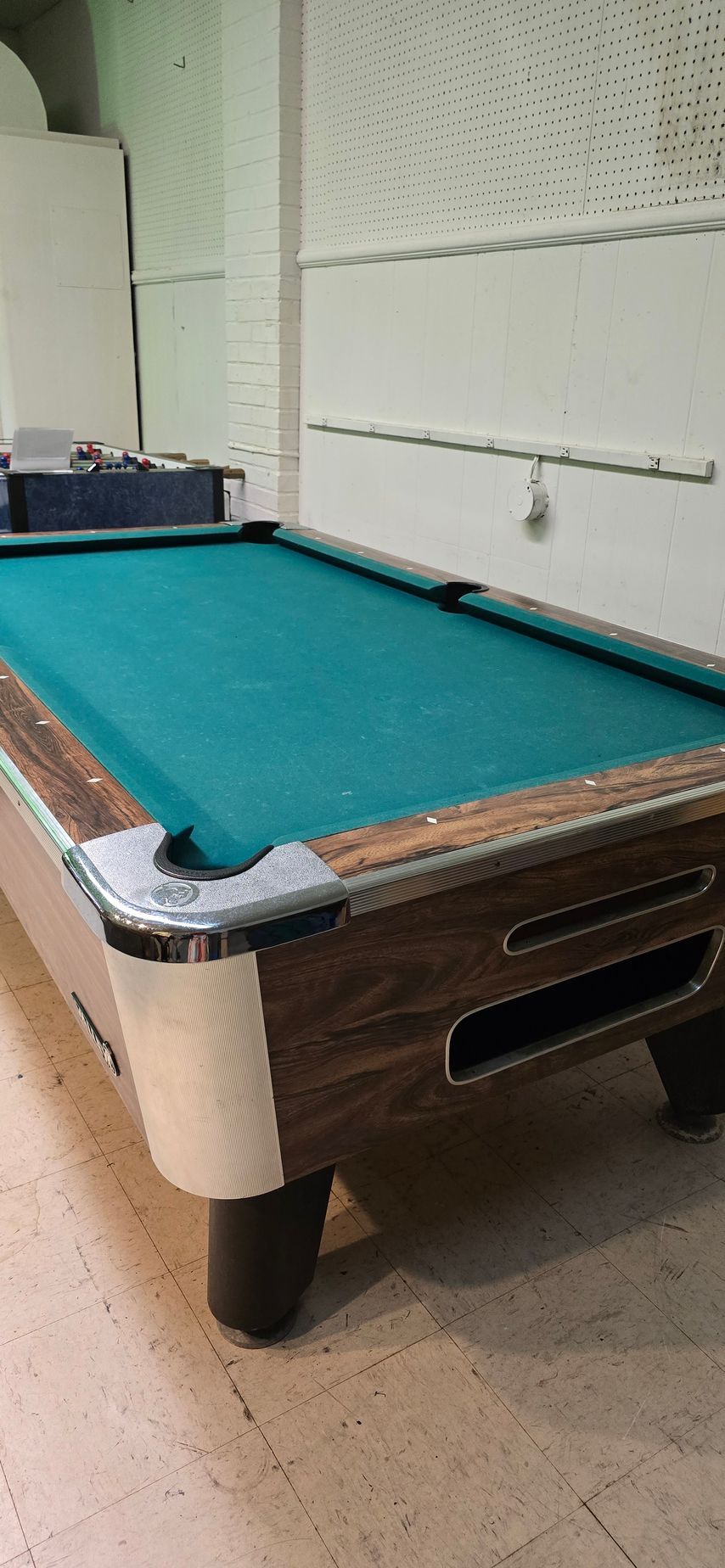 Pool table with teal felt in a room, shown beside a wall and window.