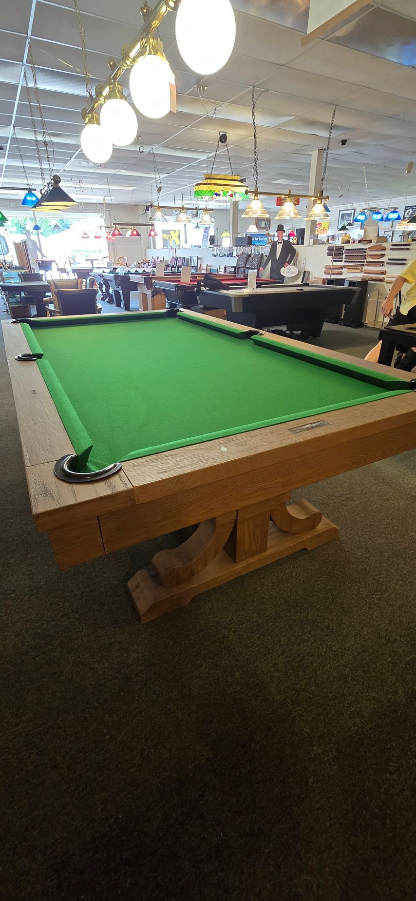Pool table with green felt in a busy indoor recreation area