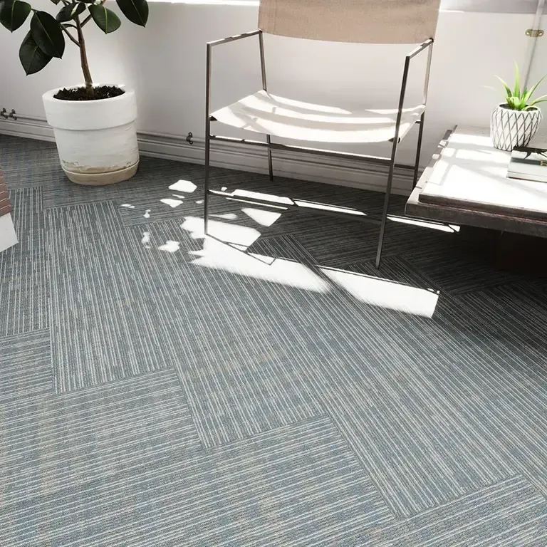 Light blue carpet tiles, chair, potted plants, side table, window.