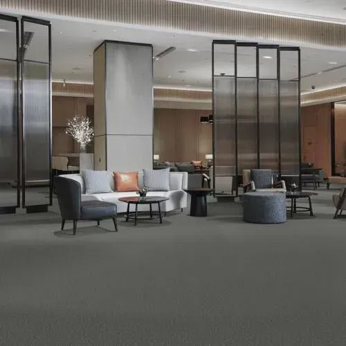 Lobby with gray carpet, seating areas, tall screens, and neutral-toned walls.