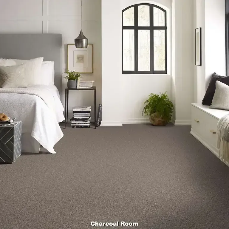 Bedroom with charcoal-colored carpet, a bed, a window, and a built-in bench.