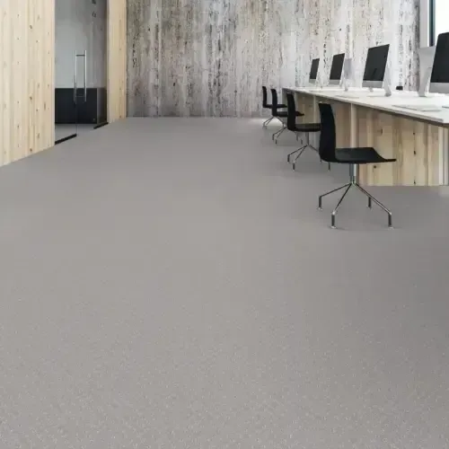 An empty office space with gray flooring, wood paneling, and computers.