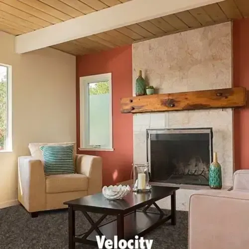 Living room with fireplace, beige walls, red accent wall, armchair, coffee table, and wood ceiling.
