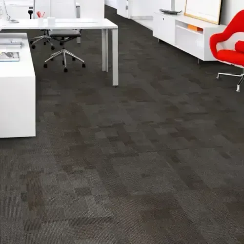 Dark gray patterned carpet in a modern office with white desks and a red chair.