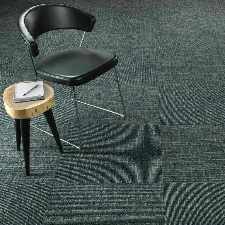 Black chair and small table with notebook on patterned blue carpet.