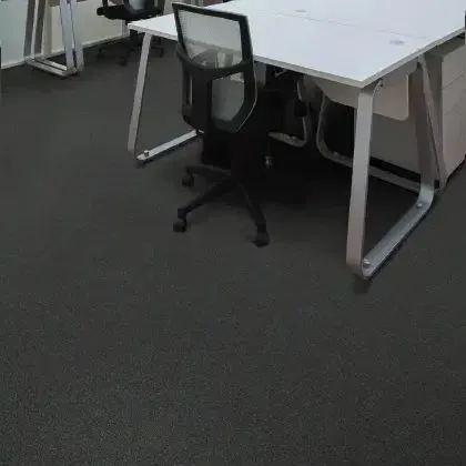 Black office chair at a white desk in a room with black flooring.