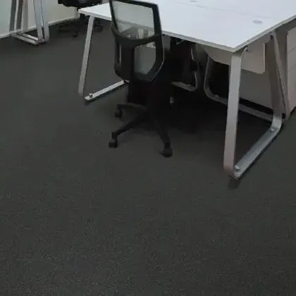 Office space with a white desk, black chair, and dark gray flooring.