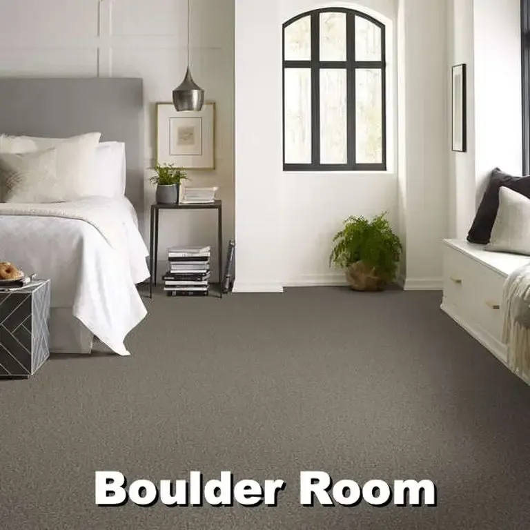 Bedroom with bed, side table, window seat, and gray carpet labeled 