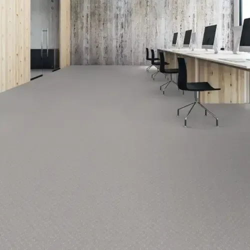 An empty office space with gray flooring, wood paneling, and computers.