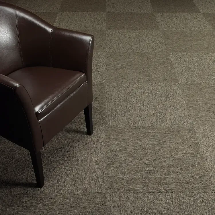 Brown leather armchair on brown square patterned carpet.