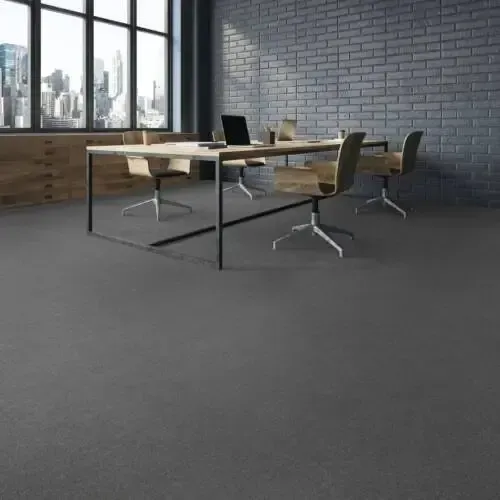Modern office space with a dark gray carpet, a meeting table, chairs, and a cityscape view.