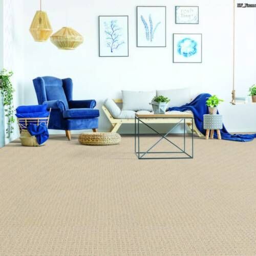 Cozy living room with beige carpet, blue armchair, light wooden couch, and wall art.