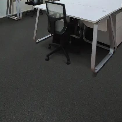 Black office chair at a white desk in a room with black flooring.