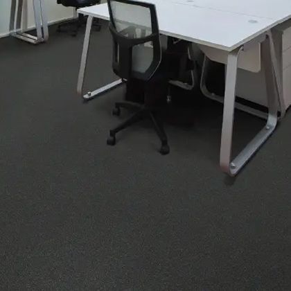 Office space with a white desk, black chair, and dark gray flooring.