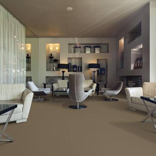 A modern living room with beige carpet, seating areas, built-in shelves, and a fireplace.