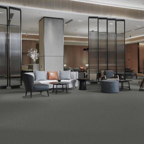 Lobby with gray carpet, seating areas, tall screens, and neutral-toned walls.