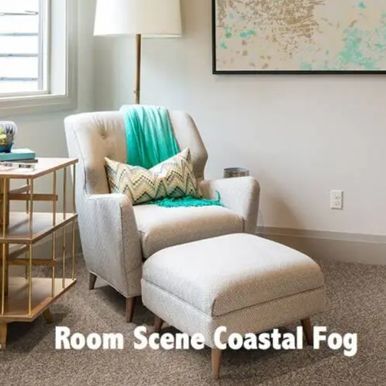 Cozy reading nook: Armchair, ottoman, tall lamp, art, and side table by a window; teal accents.