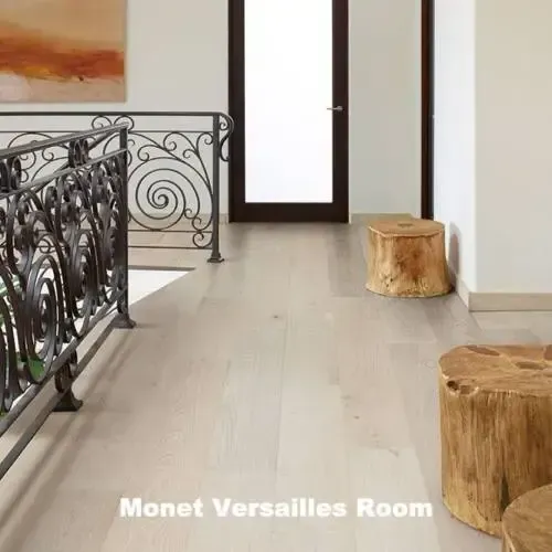 Hallway with light wood floors, ornate railing, wooden stools, and a doorway.