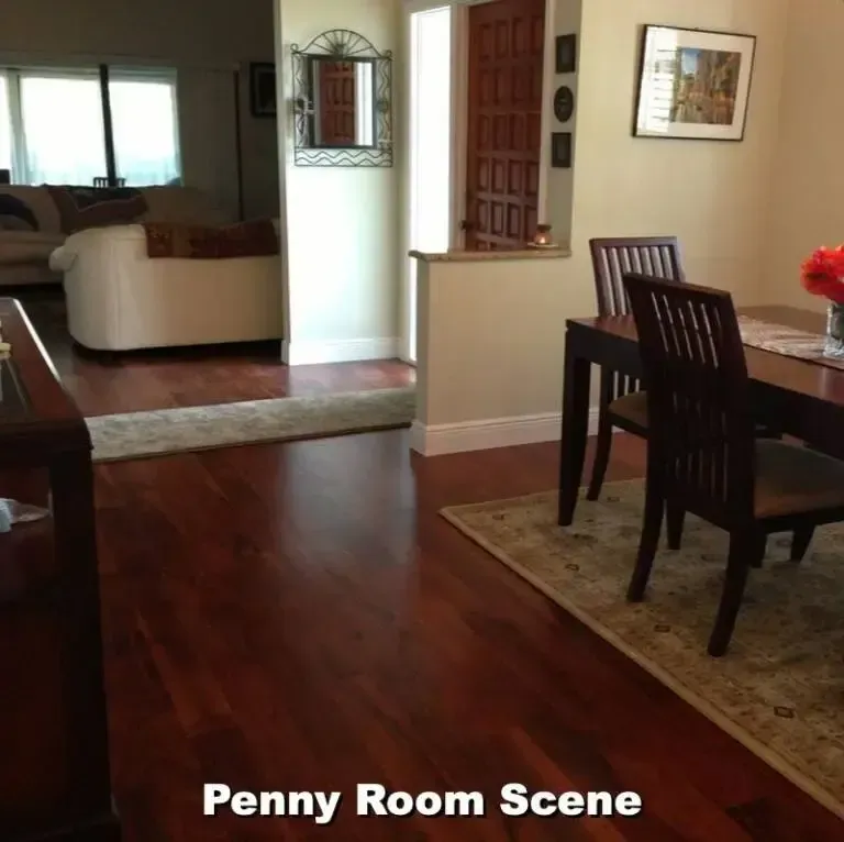 View of a dining room with dark wood table and chairs, hardwood floor, and a view into the living room.