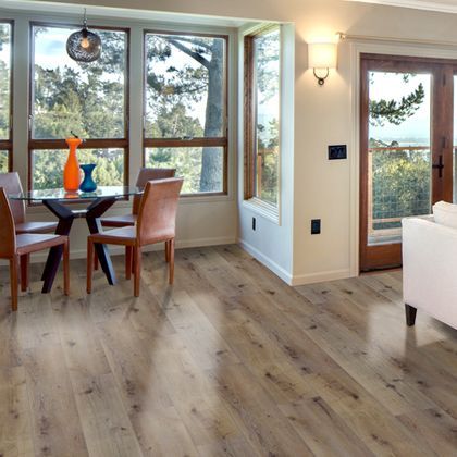 Dining room with wood flooring, table, chairs, windows, and vases.