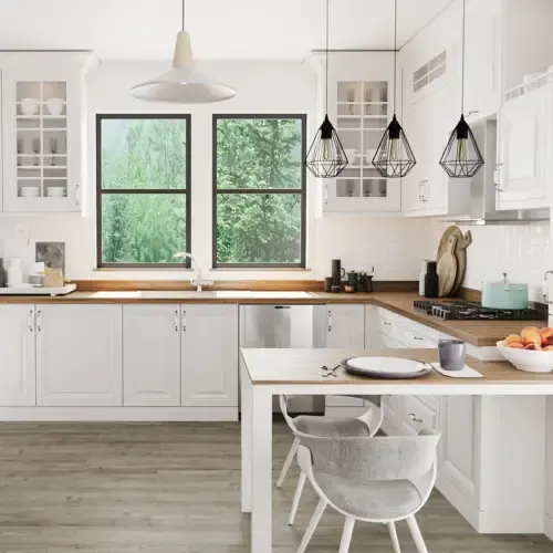 White kitchen with wooden countertops, windows, and pendant lights. A table with chairs is in the foreground.