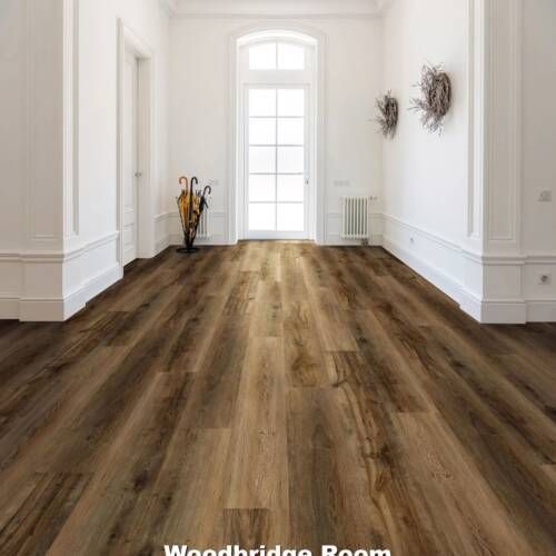 Hallway with wood-look flooring, white walls, and a door at the end. An umbrella stand and wall decorations are present.