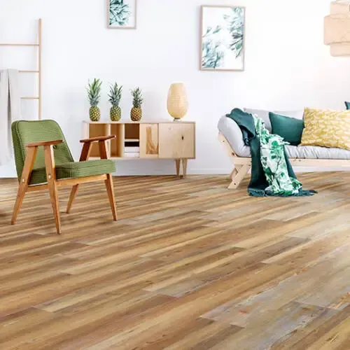 Living room with wood flooring, green chair, wooden cabinet with pineapples, couch, and wall art.