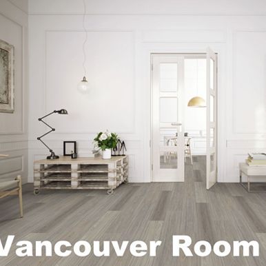 A bright room with light grey wood-look floors, white walls and a cabinet, and an open doorway.