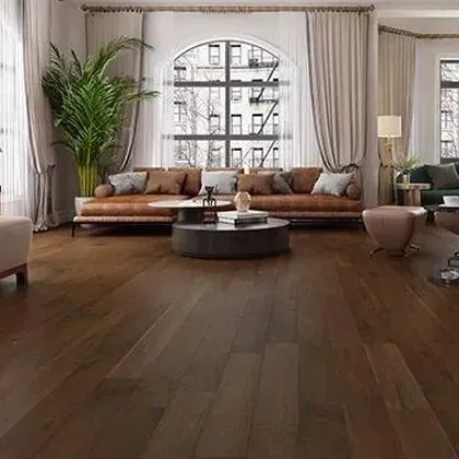 A living room with dark hardwood floors, large windows, and a leather sofa.