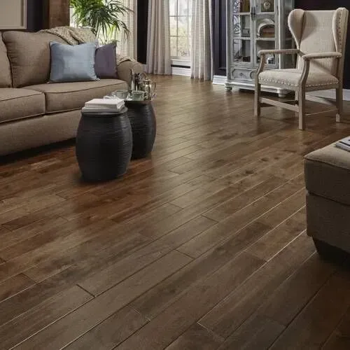 Living room with brown hardwood flooring, sofa, armchair, and black accent tables.