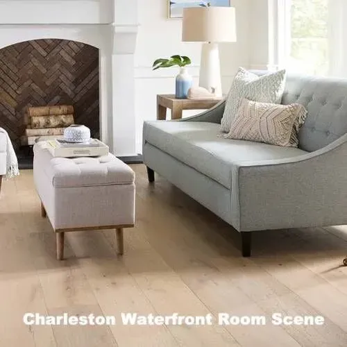 Living room with gray sofa, ottoman, and fireplace with wood floors.