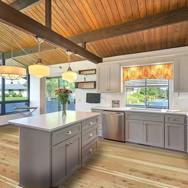 Kitchen with light wood floor, gray cabinets, white countertops, wood ceiling, and island.
