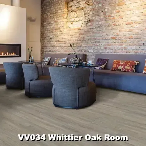 Cozy lounge area with gray seating, a fireplace, exposed brick wall, and wood-look flooring.