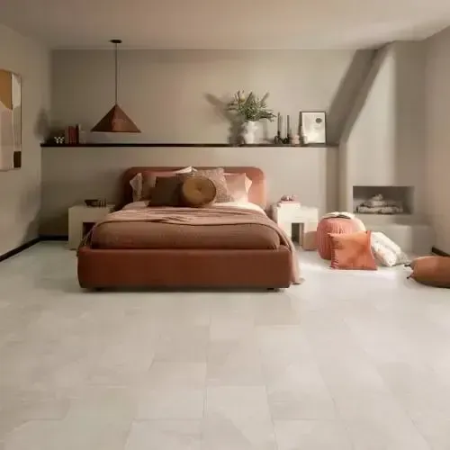 Bedroom with a low, brown bed, beige walls, and light gray floor tiles. Decorative items on a shelf.