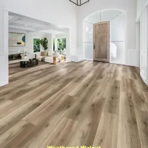 A spacious entryway with weathered walnut-colored wood flooring, leading to a living room and a wooden door.