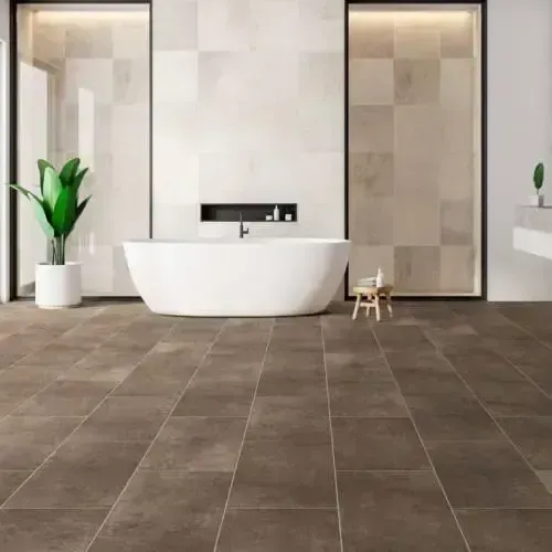 Bathroom with a white tub, brown tile floor, and light brown wall tiles. A potted plant stands near the tub.