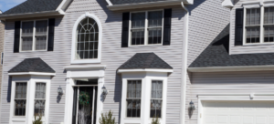 Gray two-story house with white trim, arched window, and attached garage.