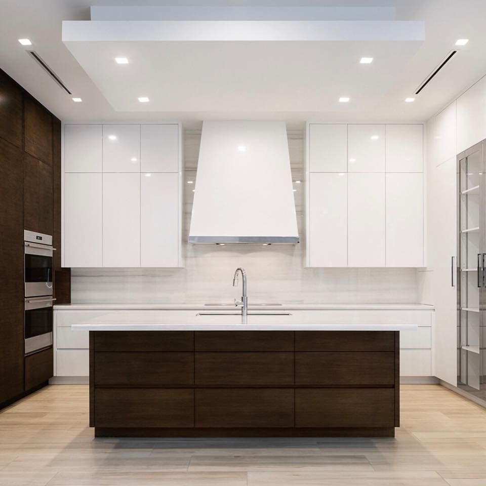 Modern kitchen with white cabinets, dark wood island, and stainless steel range hood