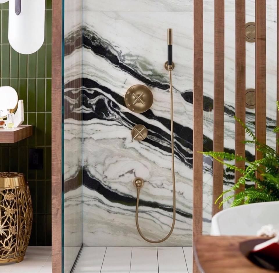 Luxurious shower with gold fixtures, green tiles, and dramatic marble wall