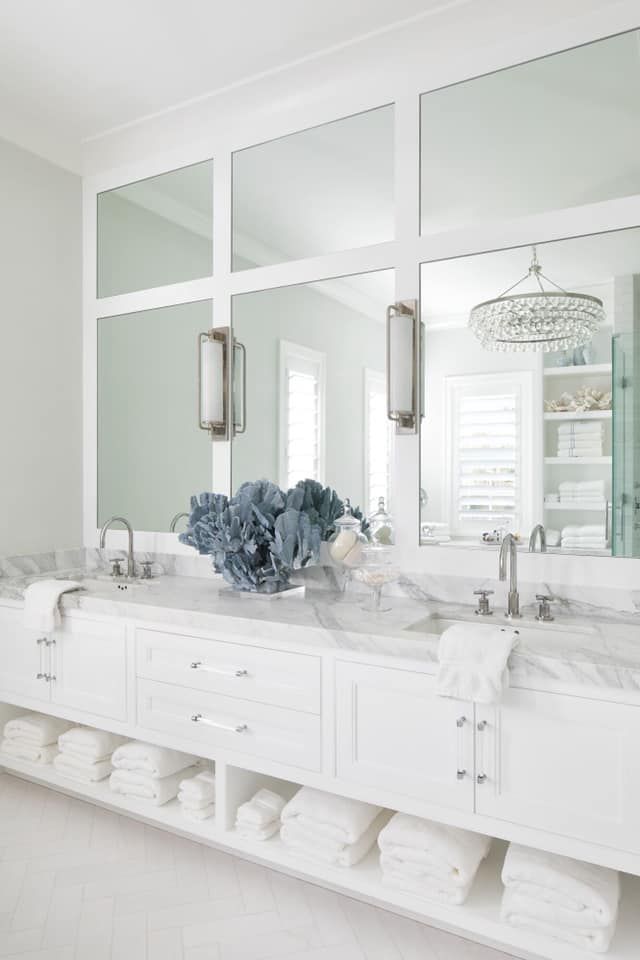White bathroom with large mirrors, double vanity, and blue floral arrangement